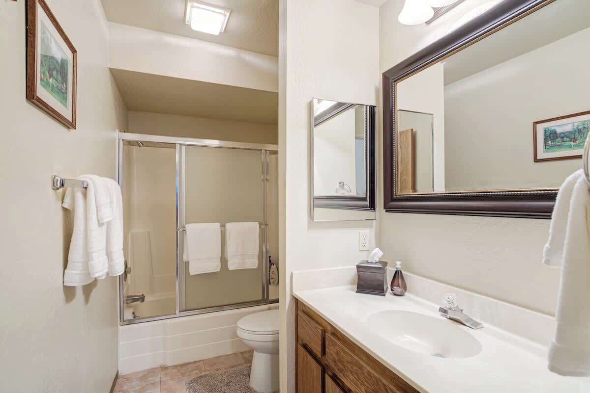 A bathroom with a glass-enclosed shower, a sink with a mirror, and a toilet.