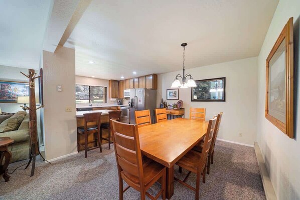 A spacious kitchen with wooden cabinets, a dining table with chairs, and a hanging light fixture. - Caddyshack - 35 Aspen Circle (Plumas Eureka)