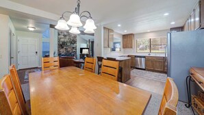 A spacious kitchen with a large wooden table, wooden cabinets, and a stainless steel refrigerator. - Caddyshack - 35 Aspen Circle (Plumas Eureka)