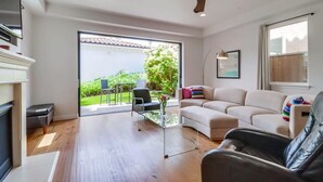 Una sala moderna con un sofá, una mesa de centro de vidrio, una chimenea y un ventilador de techo.