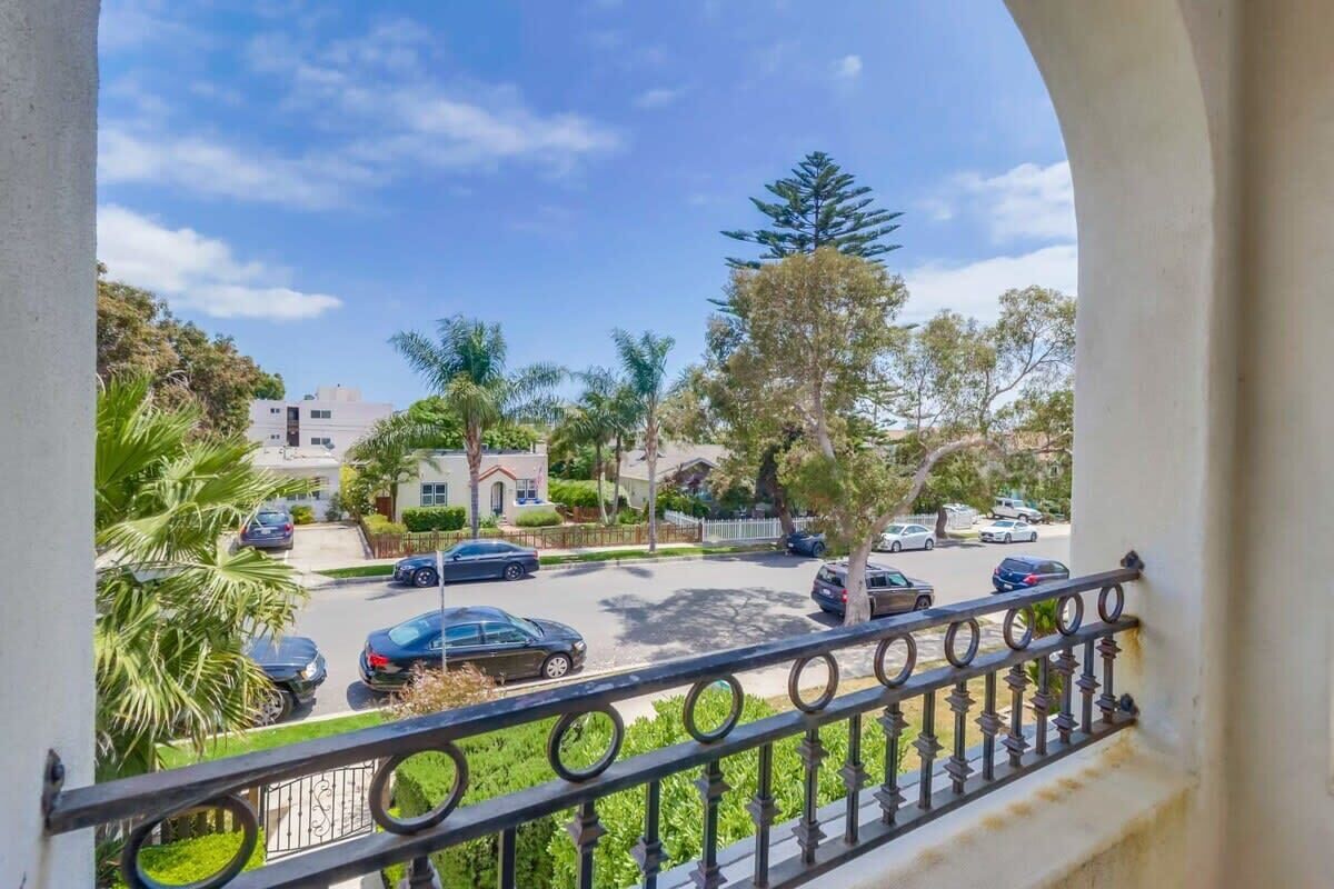 Una calle residencial con coches estacionados, palmeras y casas.