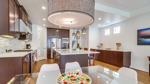 Una cocina moderna con armarios de madera oscura, una isla central y una mesa de comedor de vidrio.