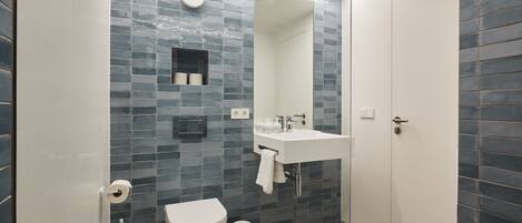 A modern bathroom with a toilet, sink, and mirror.