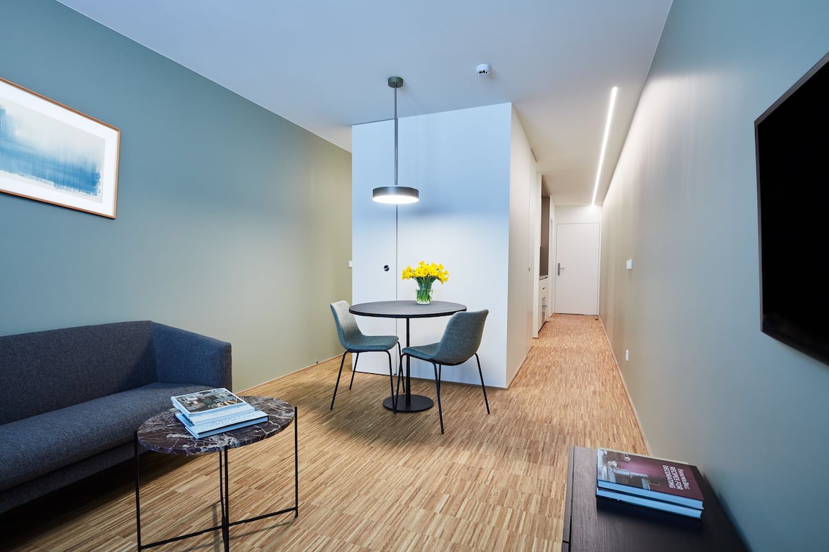 Quarto moderno com sofá, uma mesa redonda pequena e um espaço de refeições com cadeiras.