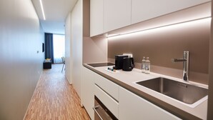 Een moderne keuken met een roestvrijstalen spoelbak, een koffiezetapparaat en een klein aanrecht.