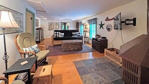 Een gezellige woonkamer met een bank, fauteuils, een bijzettafeltje en een open haard.