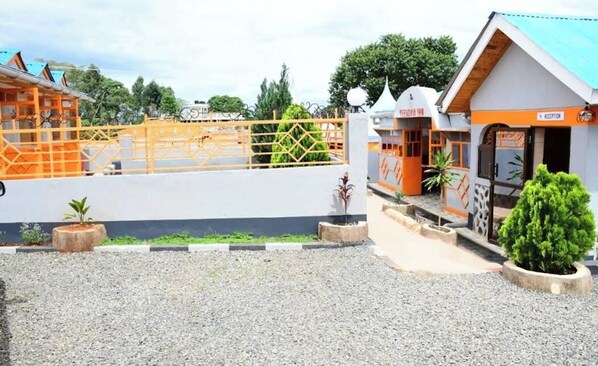 A reception area with a sign, a gated entrance, and a small garden with a tree. - Reevonia Inn  (Kapsabet)