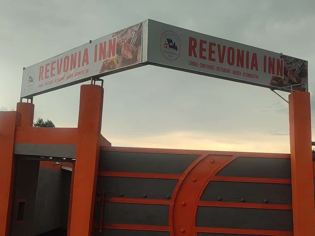 Señal de REEVONIA INN que anuncia sus servicios, incluyendo un salón, salas de conferencias, restaurante, jardín y alojamiento.