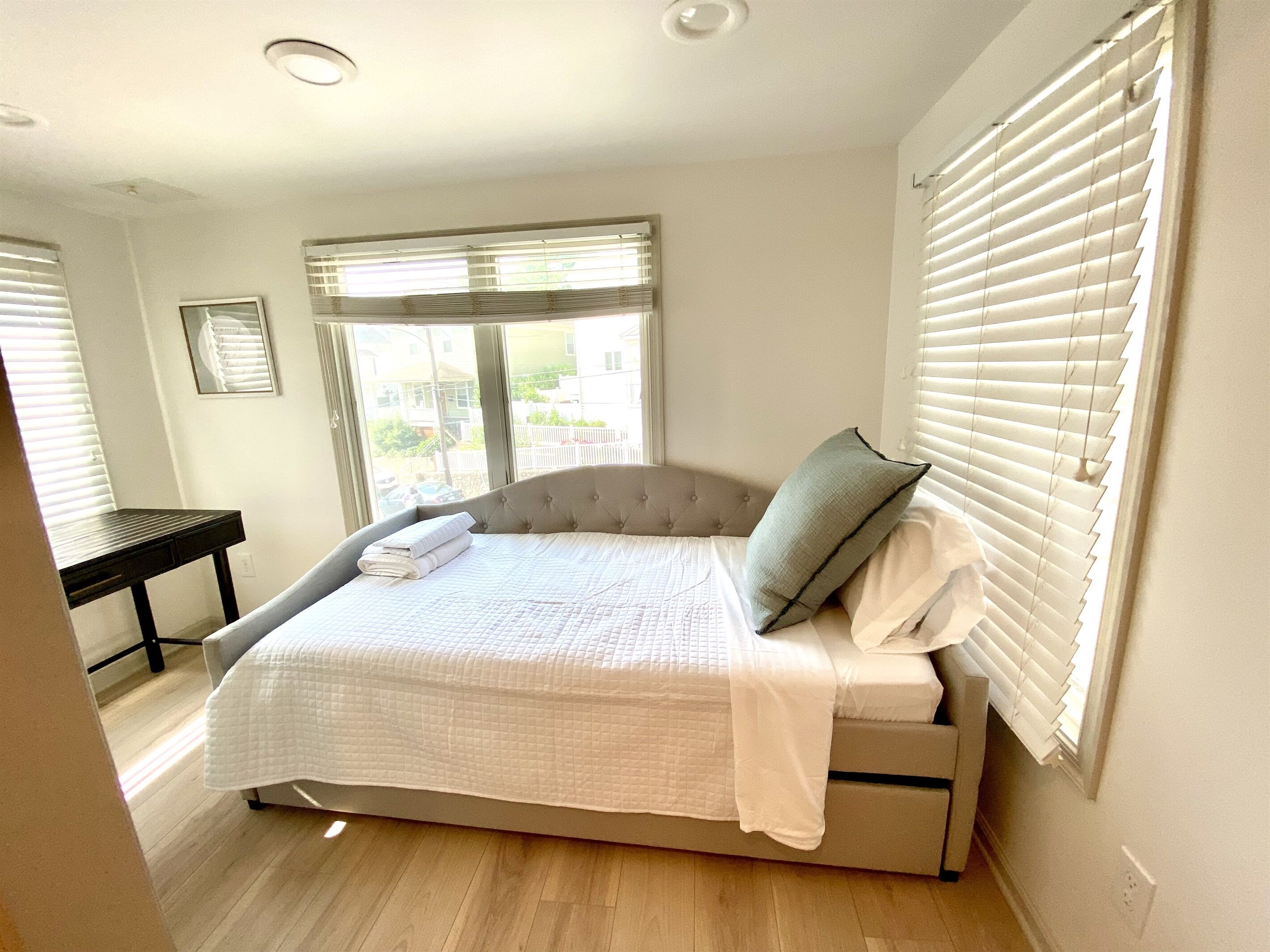 A bedroom with a bed, a bedside table, and a window with blinds.