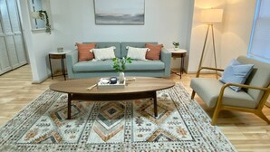A living room with a light blue sofa, a wooden coffee table, a patterned rug, and a floor lamp. - 2 King Beds + quiet + ground floor A (Norfolk)