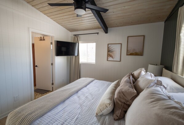 A bedroom with a bed, a ceiling fan, a TV, and a window with curtains. - Coral Point - Updated Cozy 4 bedroom w/ Salt Water Pool (Virginia Beach)