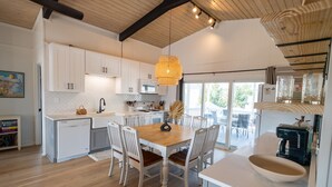 Una cocina moderna con armarios blancos, una mesa de comedor de madera y una lámpara colgante.