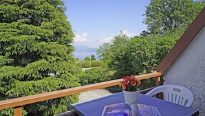 Un balcon avec une table, une chaise et un pot de fleurs.