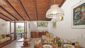 Un coin repas avec une table en bois dressée pour le repas, un lustre et des œuvres d’art accrochées aux murs.