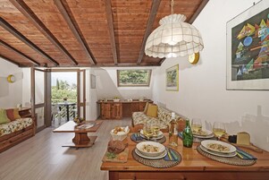 Ein Essbereich mit einem Holztisch, der für eine Mahlzeit gedeckt ist, einer Kandelaber und Kunstwerken an den Wänden.
