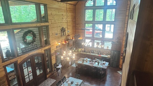 A spacious dining area with a long table set for six, surrounded by wooden walls and large windows.