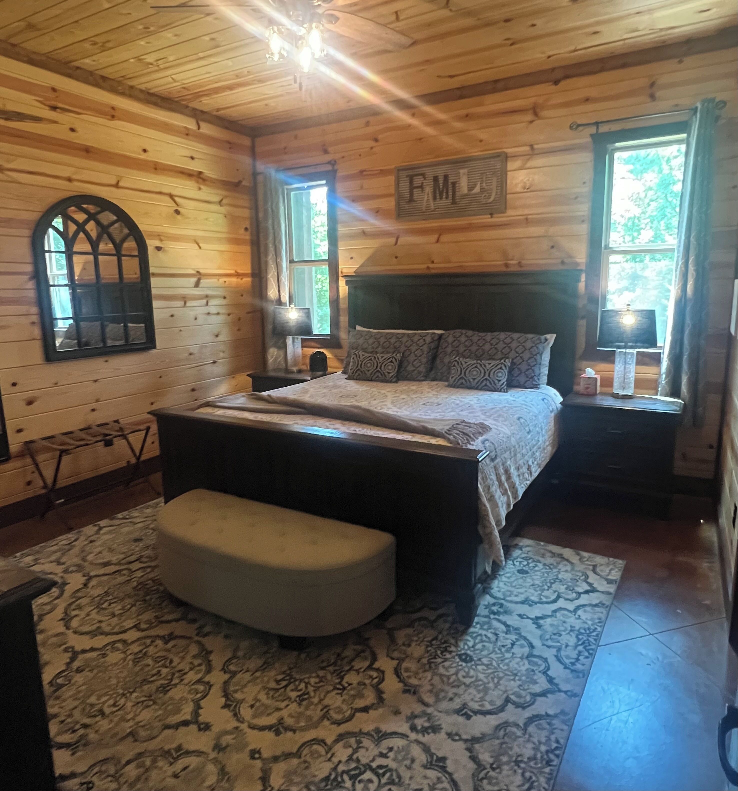 Ein Schlafzimmer einer Holzhütte mit Bett, Bank und zwei Nachttischlampen.
