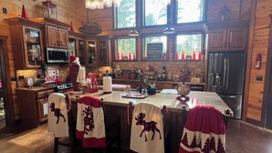 A cozy cabin-style kitchen with wooden walls, large windows, and a central island.