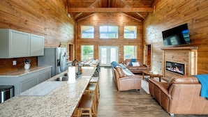 Un intérieur spacieux de chalet en bois, comprenant une cuisine, un coin repas et un salon.