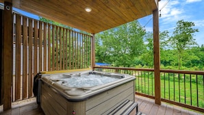 Un bain à remous sur une terrasse en bois, avec vue sur un paysage verdoyant.