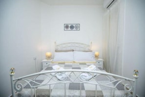 Une chambre à coucher bien rangée, avec un lit, deux tables de chevet et un tableau accroché au mur.