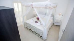 A bedroom with a four-poster bed, a bedside table, and a nightstand. - Elizabeth House (Siracusa)