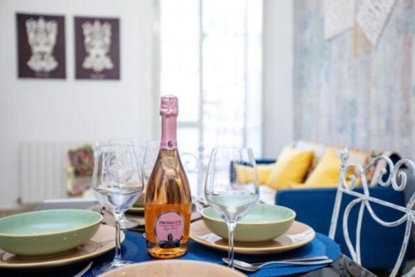 Une table à manger avec une bouteille de Prosecco, deux verres à vin et un saladier.