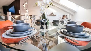A dining table set with plates, bowls, and cutlery, featuring a glass top and a vase with white flowers. - Apartment 4 - The Crescent (York)