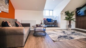 A modern living room with a sofa, a coffee table, and a TV. - Apartment 4 - The Crescent (York)