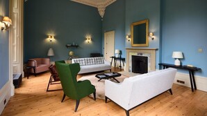 Una sala de estar con pared azul, chimenea y sillón verde.