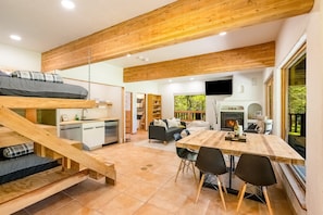 A modern interior with a loft bed, kitchen, dining area, and fireplace.