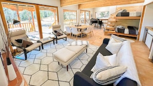 A spacious living area with a sofa, chairs, a dining table, and a piano. - Private Oasis on 15 Acres, Gas Firepit, Large Decks, Private Feel, EV/RV Hookups (Angel Fire)