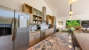 A modern kitchen with stainless steel appliances, wooden cabinets, granite countertops, and a large window with a view of greenery. - Private Oasis on 15 Acres, Gas Firepit, Large Decks, Private Feel, EV/RV Hookups (Angel Fire)