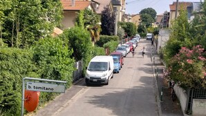 A residential street with parked cars, a sign indicating 'via b. tomitano', and lush greenery. - Face River CLOSE   historic center  Well equipped can park free well front front (Padova)