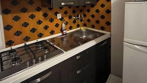 A compact kitchen with dark cabinets, a white countertop, a gas stove, a microwave, and a patterned backsplash. - Face River CLOSE   historic center  Well equipped can park free well front front (Padova)