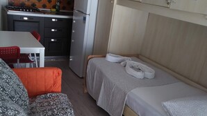 A compact room with a bed, a sofa, a small table, and a kitchenette area. - Face River CLOSE   historic center  Well equipped can park free well front front (Padova)