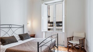 A bedroom with a bed, a chair, a window, and a door.
