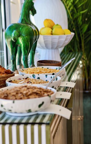 A buffet table with various dishes, including a bowl of lemons and a decorative horse figure. - Royal Boutique Hotel (Cape Town)