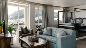Un salón espacioso con un gran ventanal, un sofá cómodo, una mesa de centro de madera y una cama con dosel.