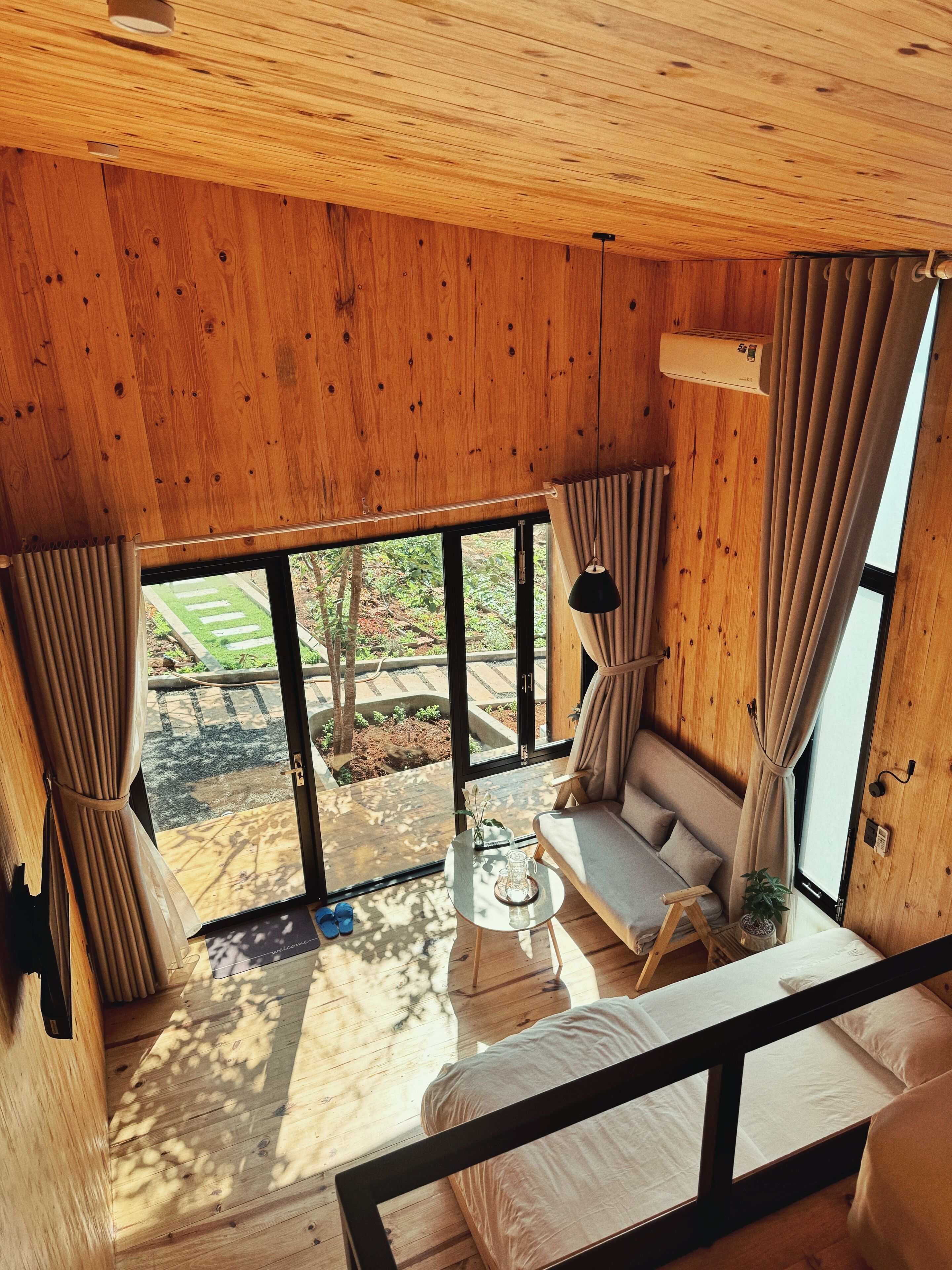 Un interior de madera con sofá, una mesita y una ventana con cortinas.