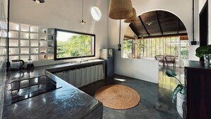 A modern kitchen with a large window, built-in shelves, a sink, and a round woven rug. - An Nhien Farmstay & Resort (Pleiku)