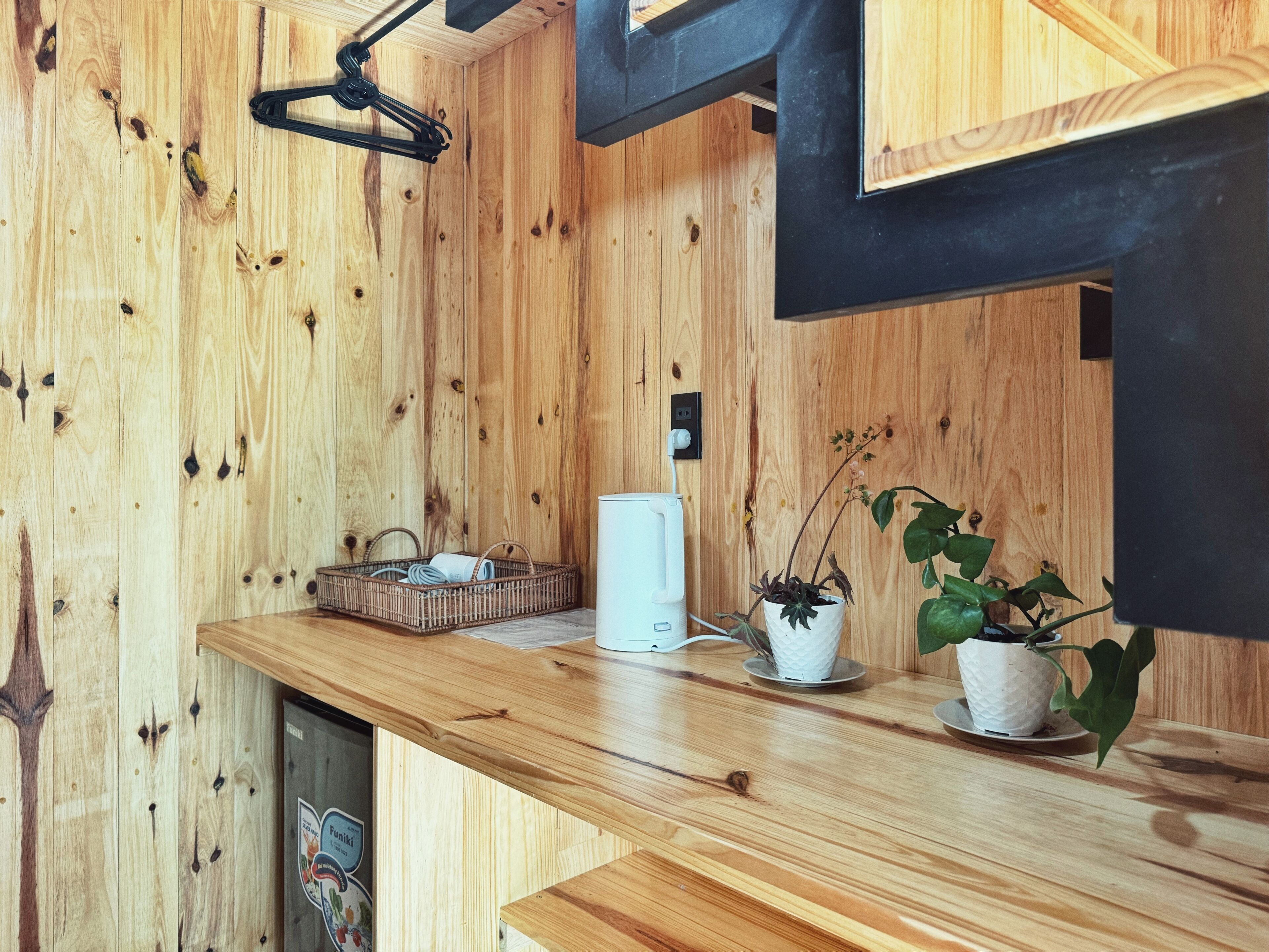 A wooden interior with a wooden counter, a white appliance, and two potted plants.