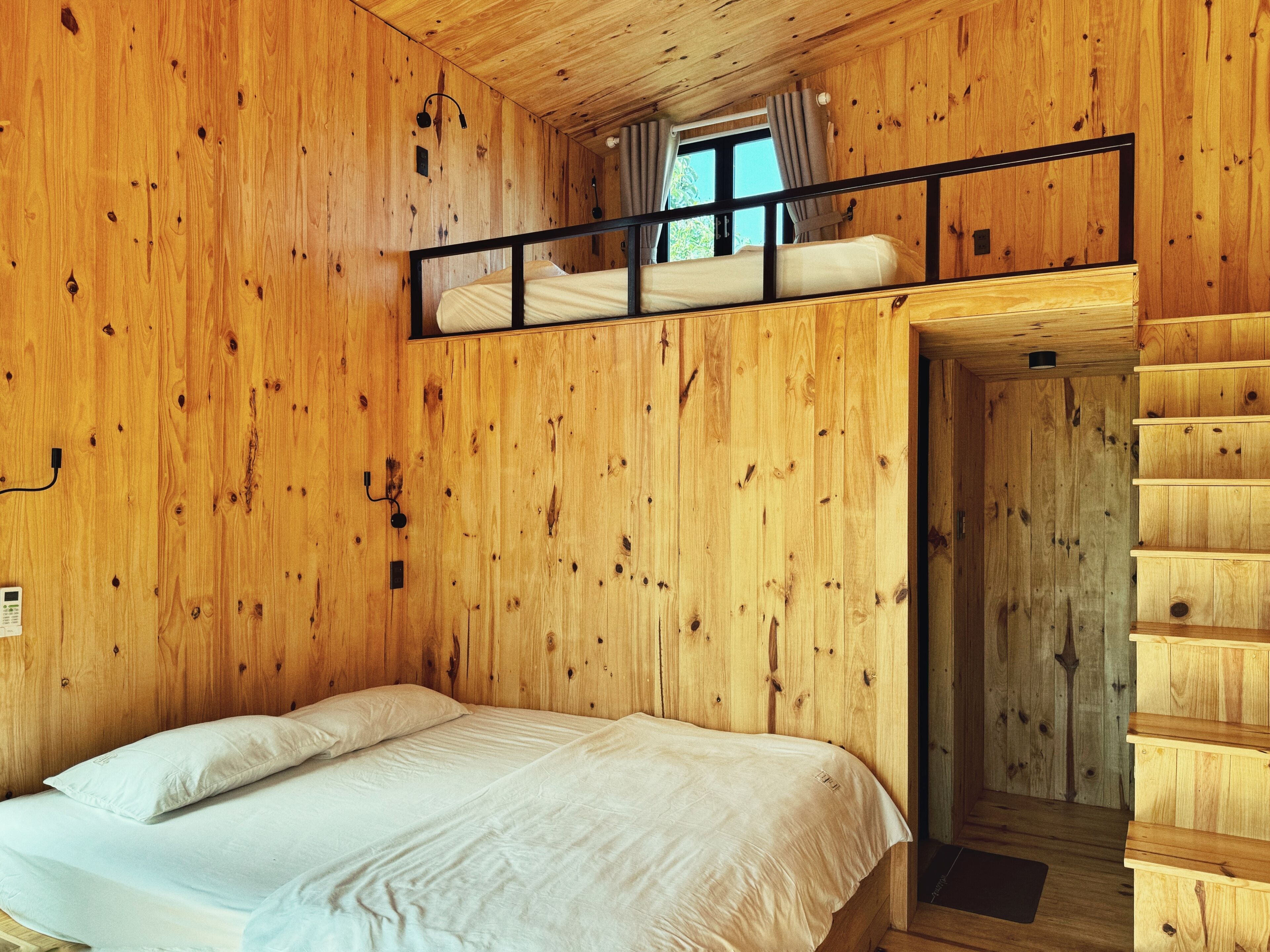A wooden cabin bedroom with a bunk bed and a single bed.