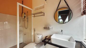 A bathroom with a toilet, shower, sink, and a mirror.