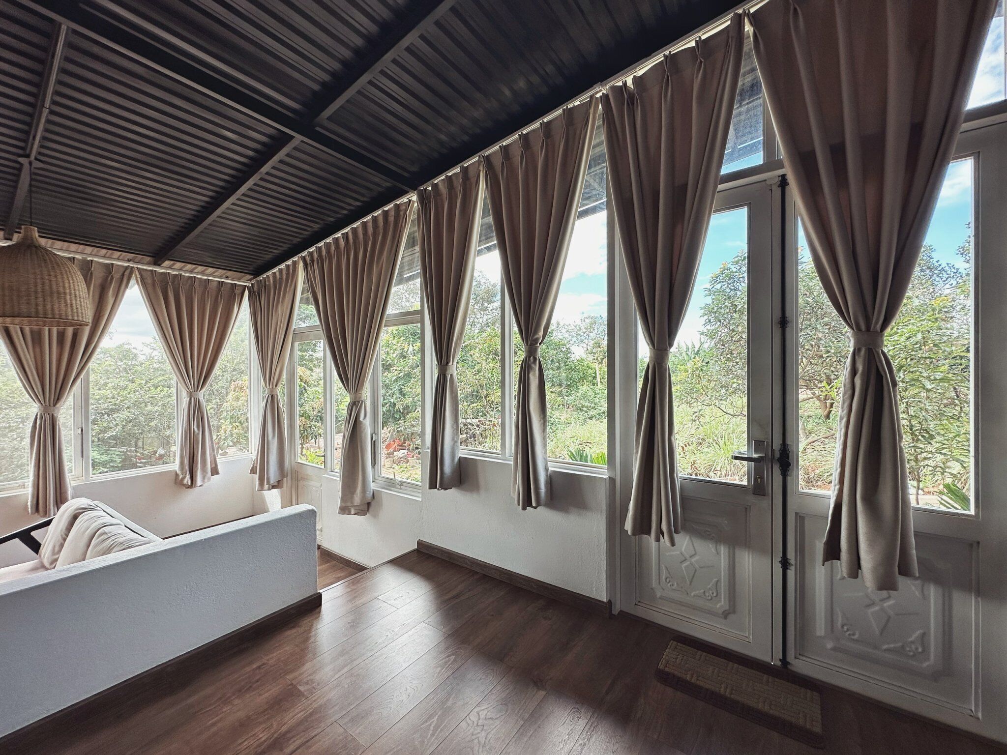 A room with large windows, wooden flooring, and a ceiling with a metal grid.
