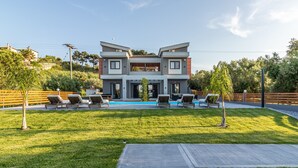 Une maison moderne à deux étages, dotée d’une piscine, d’un espace de détente extérieur et d’une pelouse bien entretenue.