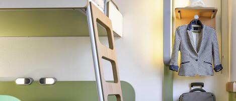 A bunk bed with a green headboard, a bedside table with a book and pen, a suitcase, and a hanging coat rack with a striped jacket.