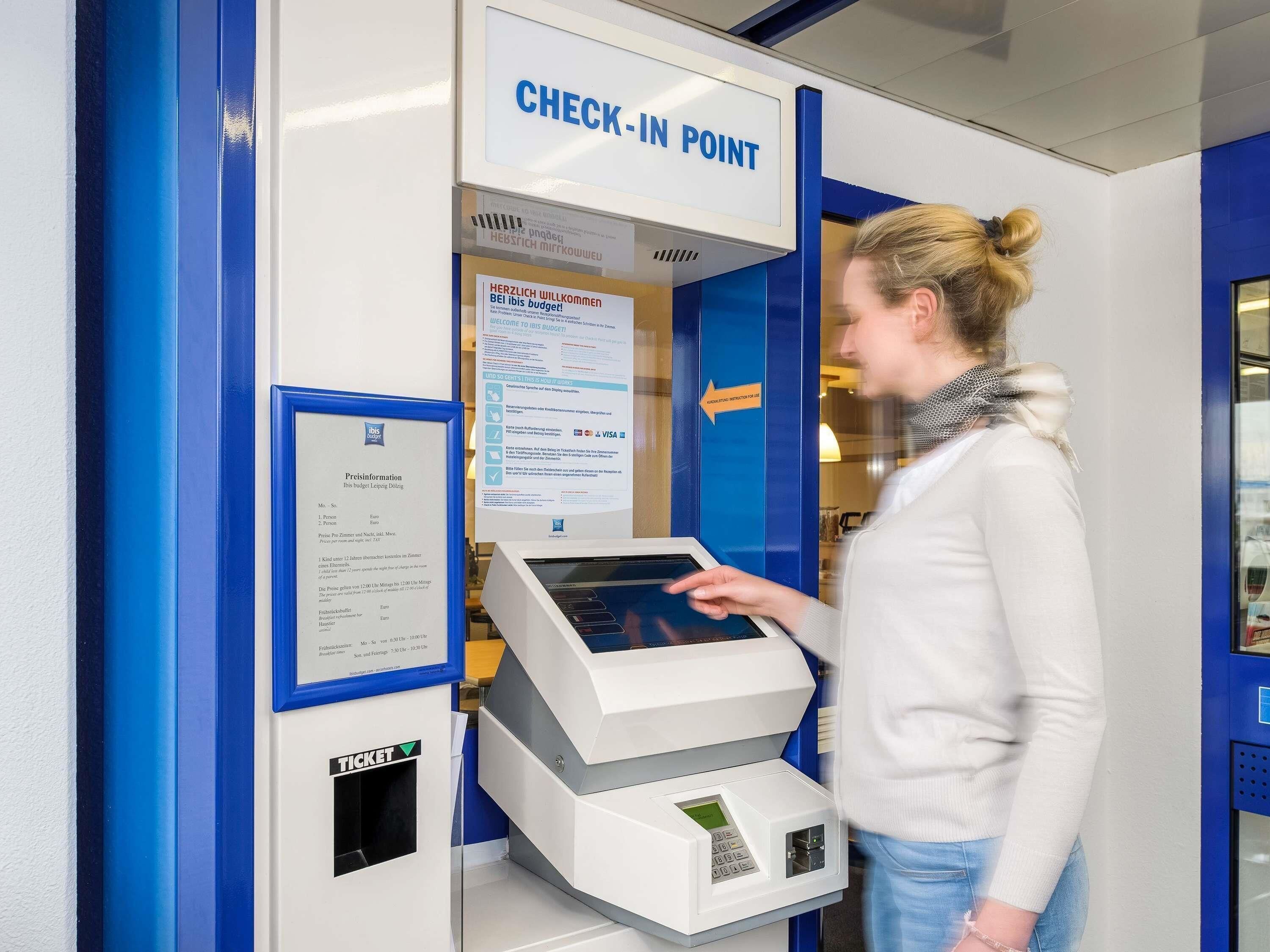 A check-in point with a digital kiosk and a ticket machine.