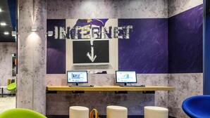 Un espace de travail moderne équipé de deux ordinateurs, d’une grande enseigne indiquant « INTERNET » et de sièges aux couleurs vives.