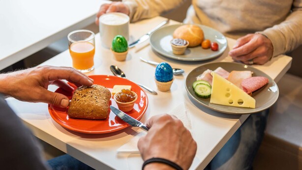 Un desayuno con diversos alimentos en platos, incluyendo pan, queso y un muffin.